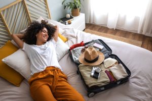 Woman lied down on her bed with her suitcase wide open